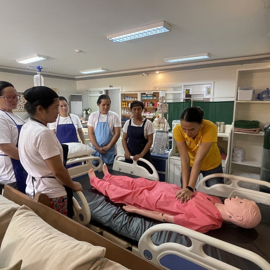 Helpers practising caregiving skills during pre-departure training